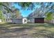 View of multiple sheds on a grassy lot surrounded by trees and a wooden fence at 8249 Cindy Dr, Zephyrhills, FL 33540