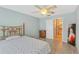 A cozy bedroom with wood flooring, a ceiling fan, a wrought iron bed frame, and a connected bath at 8457 Deauville # 8457, Pinellas Park, FL 33781