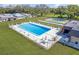 Aerial view of a community pool with lounge chairs, tables, and a shuffleboard court in the background at 8457 Deauville # 8457, Pinellas Park, FL 33781
