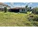 View of a backyard with overgrown lawn, and a small, screened in porch at 8537 Horizon Ln, Hudson, FL 34667