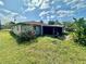 Exterior view of the home with a screened in back porch and an overgrown backyard at 8537 Horizon Ln, Hudson, FL 34667