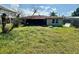Exterior view of the home with a screened in back porch and an overgrown backyard at 8537 Horizon Ln, Hudson, FL 34667