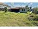 Exterior view of the home with a screened in back porch and an overgrown backyard at 8537 Horizon Ln, Hudson, FL 34667