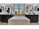Bathroom featuring an undermount tub, contrasting dark vanities and a central window providing natural light at 6927 Crestpoint Dr, Apollo Beach, FL 33572