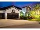Charming home featuring a two-car garage, manicured lawn, and mature landscaping at twilight at 6927 Crestpoint Dr, Apollo Beach, FL 33572