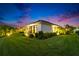 A well manicured lawn wraps around this modern home at dusk, showcasing the landscaping and exterior at 6927 Crestpoint Dr, Apollo Beach, FL 33572