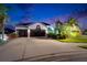 Charming home featuring a two-car garage, manicured lawn, and mature landscaping at twilight at 6927 Crestpoint Dr, Apollo Beach, FL 33572