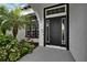 Inviting entrance with a black front door framed by windows and lush, tropical landscaping at 6927 Crestpoint Dr, Apollo Beach, FL 33572