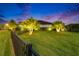 A black metal fence surrounds this home's lush, green front yard featuring manicured landscaping and illuminated palm trees at 6927 Crestpoint Dr, Apollo Beach, FL 33572