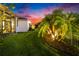 Beautiful landscaping, including illuminated palm trees, surrounds this single story home at twilight at 6927 Crestpoint Dr, Apollo Beach, FL 33572