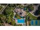 Aerial view of community amenities, including a pool, hot tub, clubhouse, tennis courts and lush landscaping at 1010 Blue Heron Way, Tarpon Springs, FL 34689