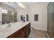 Bathroom with double sinks, marble countertop, wood cabinetry, and glass shower with tan tile and trim at 1010 Blue Heron Way, Tarpon Springs, FL 34689