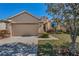 Single-story home with a two-car garage, manicured landscaping, and a charming entrance under a sunny sky at 1010 Blue Heron Way, Tarpon Springs, FL 34689