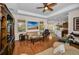 Open-concept living room with hardwood floors, a ceiling fan, comfortable seating, and a view into the kitchen at 1010 Blue Heron Way, Tarpon Springs, FL 34689