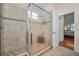 Bathroom shower featuring glass doors, tan tile and trim, and a view into the adjoining bedroom at 1010 Blue Heron Way, Tarpon Springs, FL 34689