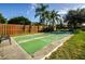 Outdoor shuffleboard court with fresh green surface, bordered by trees, a wooden fence, and a wrought iron bench at 1010 Blue Heron Way, Tarpon Springs, FL 34689