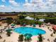 Aerial view of a sparkling community pool surrounded by lounge chairs, umbrellas, and lush landscaping at 1020 New Winsor Loop # 46, Sun City Center, FL 33573