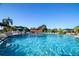 Serene community pool featuring clear blue water, lounge chairs, and shady umbrellas for relaxation and recreation at 1020 New Winsor Loop # 46, Sun City Center, FL 33573