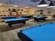 Recreation room showcasing five billiard tables with blue felt, overhead lighting, and ceiling fans at 1034 Mcdaniel St # 1034, Sun City Center, FL 33573