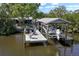 Waterfront property featuring a dock with a boat lift, seating, and covered area for relaxation and waterfront enjoyment at 107 6Th Nw St, Ruskin, FL 33570