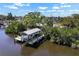 Waterfront property featuring a boat dock and lift on a sunny day, surrounded by lush greenery at 107 6Th Nw St, Ruskin, FL 33570