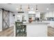 Open kitchen with eat-in island, stainless appliances, and a stylish barn door at 107 6Th Nw St, Ruskin, FL 33570