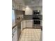 Well-maintained kitchen with stainless steel appliances, tile backsplash and countertops, and white cabinets at 111 Woodland Pl, Osprey, FL 34229