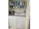 A laundry room includes a white washer and dryer, with shelves for storage above appliances at 111 Woodland Pl, Osprey, FL 34229