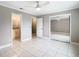 Bedroom with ensuite bathroom, mirrored closet, white tile floor, ceiling fan and neutral gray walls at 13719 Juniper Blossom Dr, Tampa, FL 33618