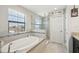 Bright bathroom featuring a soaking tub, glass shower, and tile accents at 14637 Red Castle Ave, Lithia, FL 33547