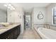 Bathroom showcasing double sinks, soaking tub, and neutral tiling at 14637 Red Castle Ave, Lithia, FL 33547