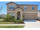 Charming two-story home featuring an arched entryway, a well-manicured lawn, and an attached two-car garage at 14637 Red Castle Ave, Lithia, FL 33547