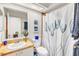 Well-lit bathroom with a sink, toilet, mirror, and shower with a floral curtain at 230 Lotus Dr, Safety Harbor, FL 34695