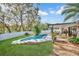 Backyard oasis features a refreshing pool, covered patio, and lush landscaping for outdoor entertaining at 230 Lotus Dr, Safety Harbor, FL 34695