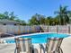 Backyard swimming pool surrounded by a wooden fence, palm trees, and two lounging chairs at 2823 St Croix Dr, Clearwater, FL 33759