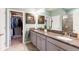 Bright bathroom featuring granite countertops, dual sinks, framed mirrors, and a view to the walk-in closet at 2914 Grand Kemerton Pl, Tampa, FL 33618