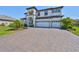 Spacious paver driveway leading to a charming two-story home with a three-car garage and manicured landscaping at 3020 Silva Wood Dr, Valrico, FL 33596