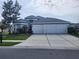 Beautiful single-story home featuring a well-manicured lawn, mature trees, and a three-car garage at 3215 Coconut Grove Rd, Land O Lakes, FL 34639