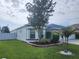 Charming home featuring a landscaped front yard with beautiful tree and decorative plants at 3215 Coconut Grove Rd, Land O Lakes, FL 34639
