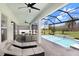 Covered patio with ceiling fans and seating area, leading to a screened in pool and spa at 32423 Rosewood Meadow Ln, Wesley Chapel, FL 33543
