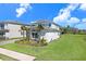 Attractive two-story home with white exterior, stone accents, and well-maintained landscaping, located near a pond at 32423 Rosewood Meadow Ln, Wesley Chapel, FL 33543