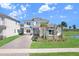 Charming two-story home with stone accents, a three-car garage and a brick paved driveway, located near a pond at 32423 Rosewood Meadow Ln, Wesley Chapel, FL 33543