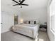 White bedroom with a ceiling fan, neutral decor, and a view into a bathroom, creating a serene atmosphere at 33064 Tulip Petal Ln, Wesley Chapel, FL 33545