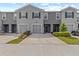 Exterior view of gray two-story townhome with front-entry garage and well-maintained landscaping at 33064 Tulip Petal Ln, Wesley Chapel, FL 33545