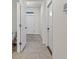 Hallway with neutral tile flooring leading to a white front door at 33064 Tulip Petal Ln, Wesley Chapel, FL 33545