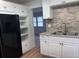 Kitchen with white cabinets, stone backsplash, stainless sink and black refrigerator at 38030 Howard Ave, Dade City, FL 33525