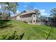 Spacious backyard featuring a lush lawn, pool enclosure, and the house with a second-story balcony at 405 Apache Trl, Brandon, FL 33511
