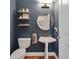 Stylish half bathroom featuring modern fixtures, floating shelves, and a unique pedestal sink for guests' convenience at 405 Apache Trl, Brandon, FL 33511