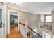 Bright hallway with hardwood floors and white railings, offering views of the living room and a bedroom at 405 Apache Trl, Brandon, FL 33511