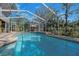 Screened pool with an umbrella table and seating area surrounded by lush greenery at 405 Apache Trl, Brandon, FL 33511